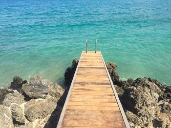 Boardwalk against turquoise sea on sunny day