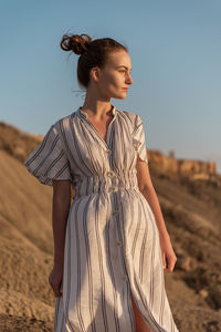 Young woman standing on land against sky