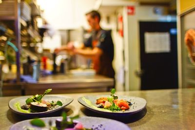 Chef working at commercial kitchen with meal in foreground