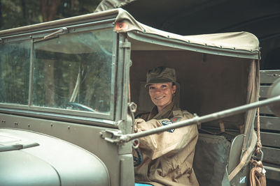 Portrait of army soldier sitting at vintage car