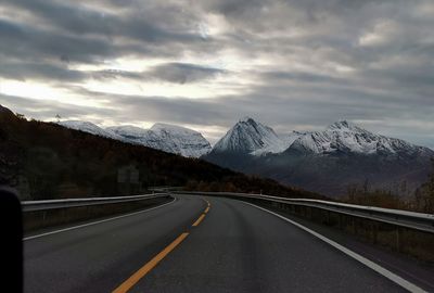 Road leading towards snowcapped mountains against sky