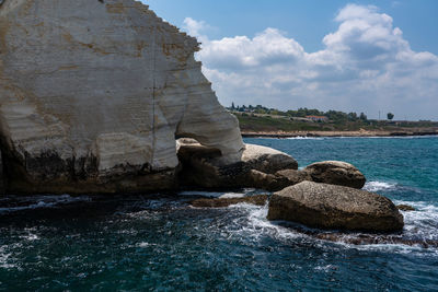 Rock formation in sea against sky