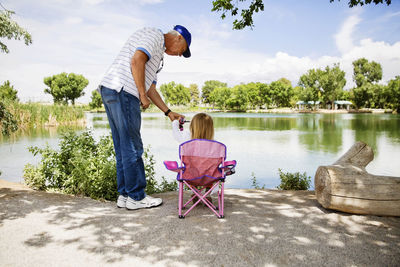 Grandfather and granddaughter fishing at lakeshore