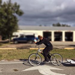 Man riding bicycle on road against sky