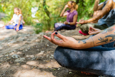 Group of reflective people with closed eyes sitting in lotus pose while practicing yoga on pathway