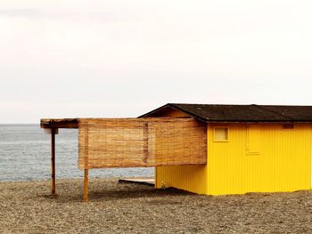 Built structure on beach by sea against clear sky