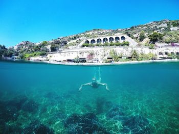 Man swimming in sea against clear blue sky