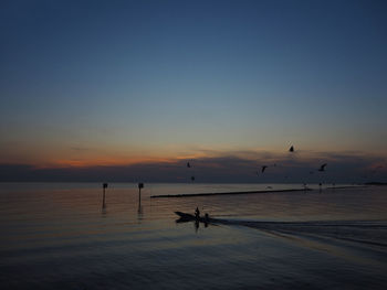 Silhouette boats in sea against sky during sunset