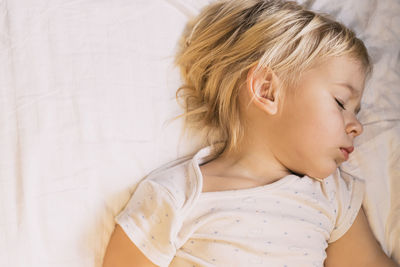 Little boy sleeping on white pillow. beautiful baby child with long blonde hair. close-up face