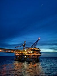 Cranes in sea against blue sky