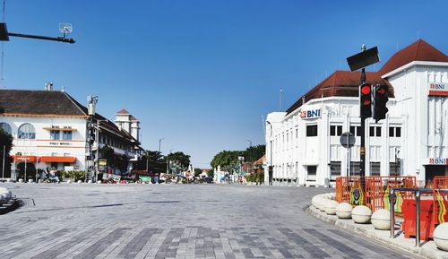 Street amidst buildings against clear blue sky