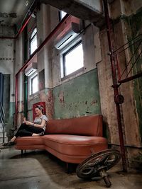 Woman sitting on sofa in abandoned room