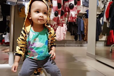 Cute baby girl looking away while sitting in clothing store