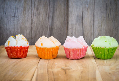 Close-up of cupcakes on wooden table against wall