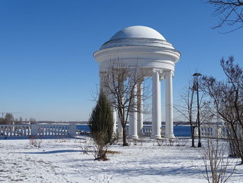 Built structure on snow covered land against blue sky