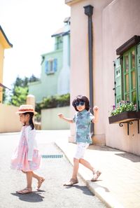 Siblings walking on road during sunny day