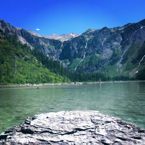 Scenic view of lake by mountains against clear blue sky