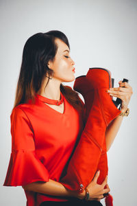 Woman puckering lips to red boots against white background