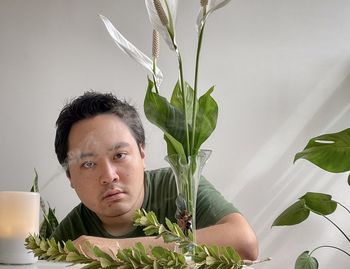 Portrait of asian man with aromatherapy diffuser, peace lilies in vase and plants.