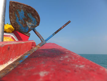 Rusty metallic oar on boat deck in sea against clear sky
