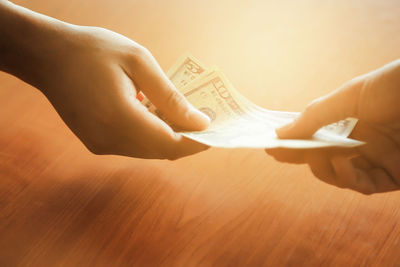 High angle view of hand holding paper at table