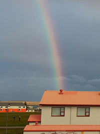 Low angle view of rainbow over buildings against sky