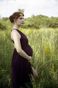 Young woman looking away while standing on field