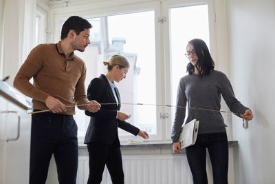 Couple taking measurements while standing with realtor in new house