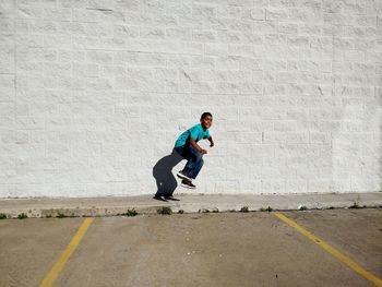 Full length of boy jumping against wall