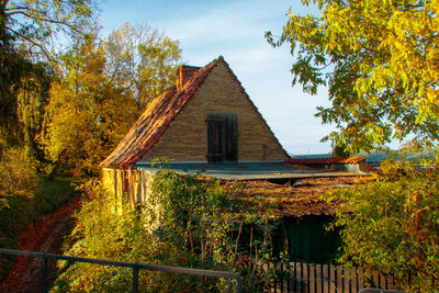 House amidst trees and buildings against sky during autumn