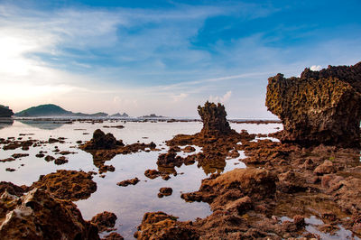 Rocks on beach against sky during sunset