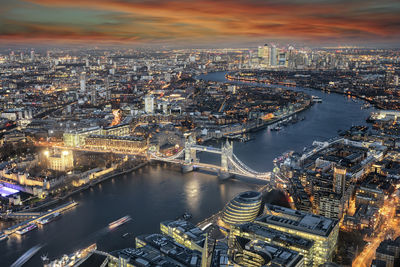 High angle view of illuminated buildings by river against sky