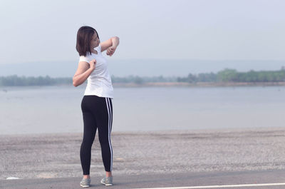 Woman standing at beach against sky