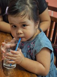 Close-up portrait of girl drinking water on table