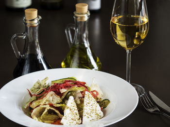 Close-up of greek salad in plate by wine served on table