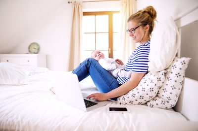 Mother with baby at home working with laptop