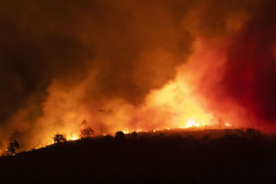 Silhouette of fire against sky at night