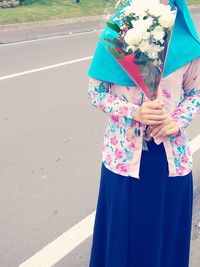 Woman holding umbrella standing on road