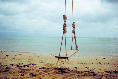 Swing on beach against sky