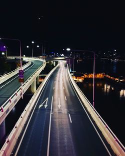 Illuminated bridge over road in city at night