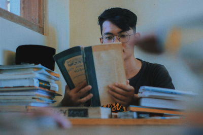 Young man reading book while sitting at home