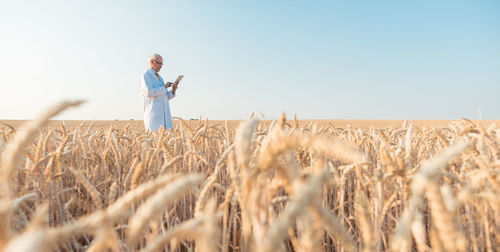 Man using digital tablet while standing amidst plants