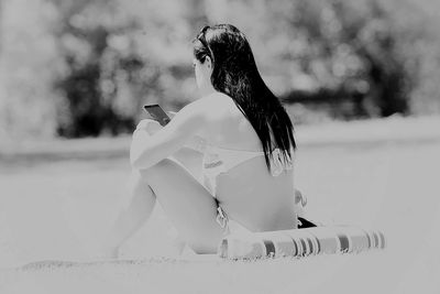 Side view of young woman using mobile phone outdoors