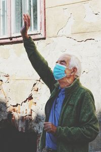 Full length of old man with grey hair wearing a coronavirus mask and greeting on the street