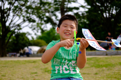 Portrait of happy boy holding toy airplane in park