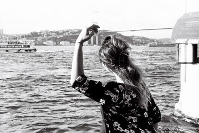 Rear view of young woman enjoying the stunning view at sea