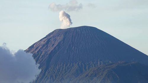 Smoke emitting from volcanic mountain against sky