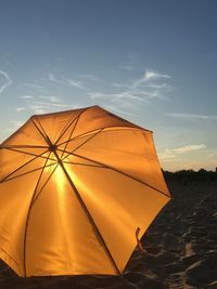 Umbrella on sand against sky