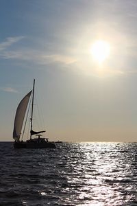 Sailboat sailing on sea against sky during sunset