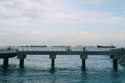 Pier on sea against cloudy sky